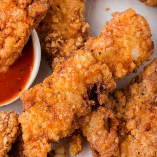 Closeup view of gluten free chicken tenders with a side of BBQ sauce