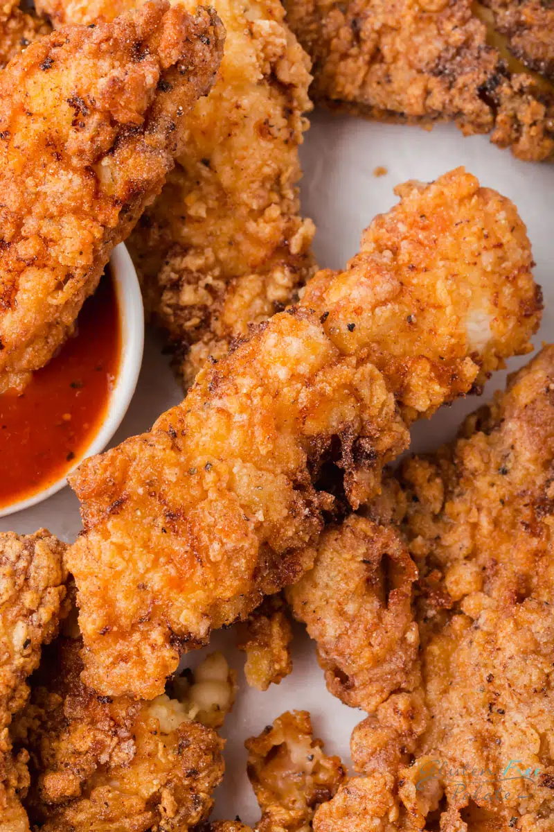 Closeup view of gluten free chicken tenders with a side of BBQ sauce
