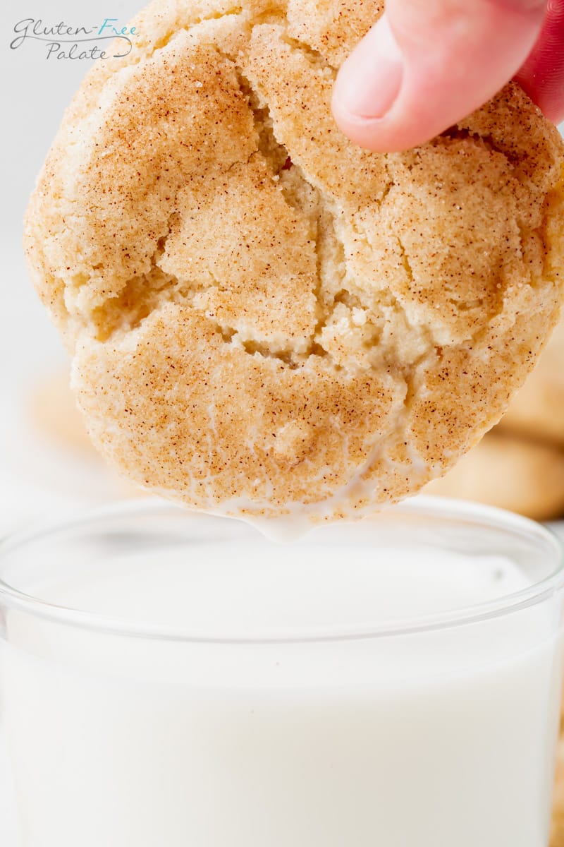 A gluten-free snickerdoodle being dunked into a glass of milk.