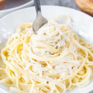 a bowl of pasta and alfredo sauce, twirled with a fork.