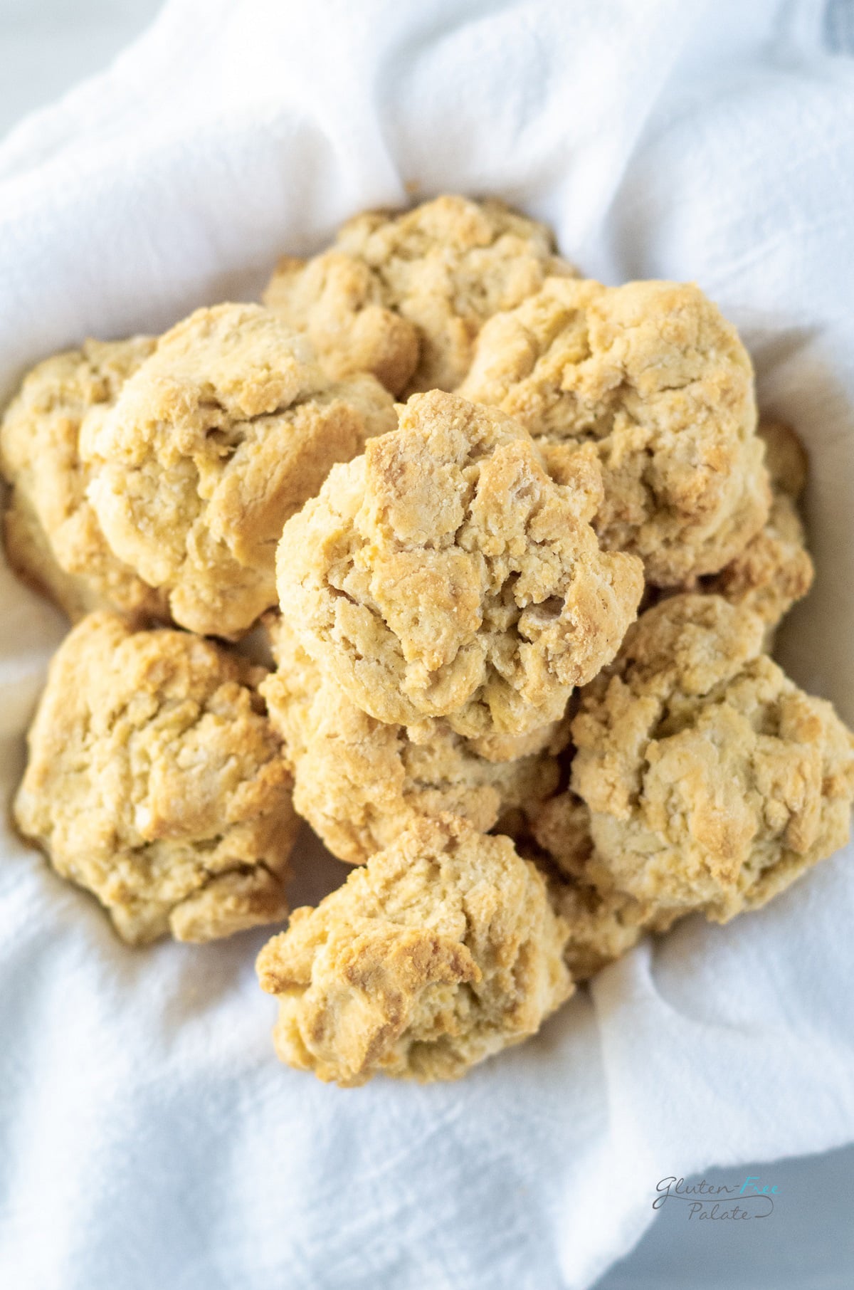 a bowl lined with a tea towel holding a dozen gluten free drop biscuits