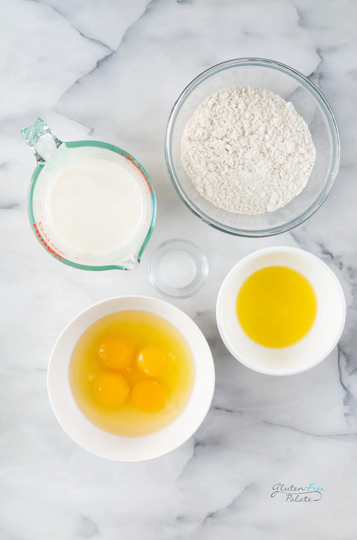 the ingredients for gluten-free popovers measured into separate bowls on a marble counter