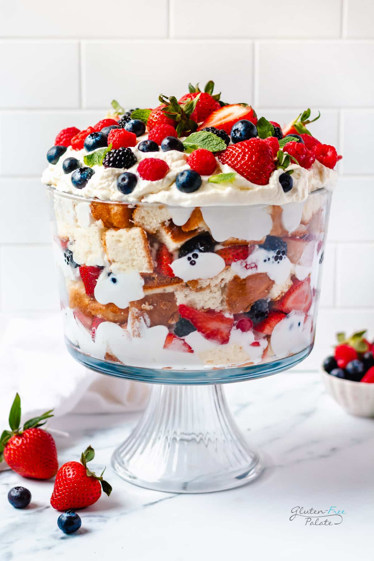 a gluten-free trifle with layers of cake, whipped cream and berries