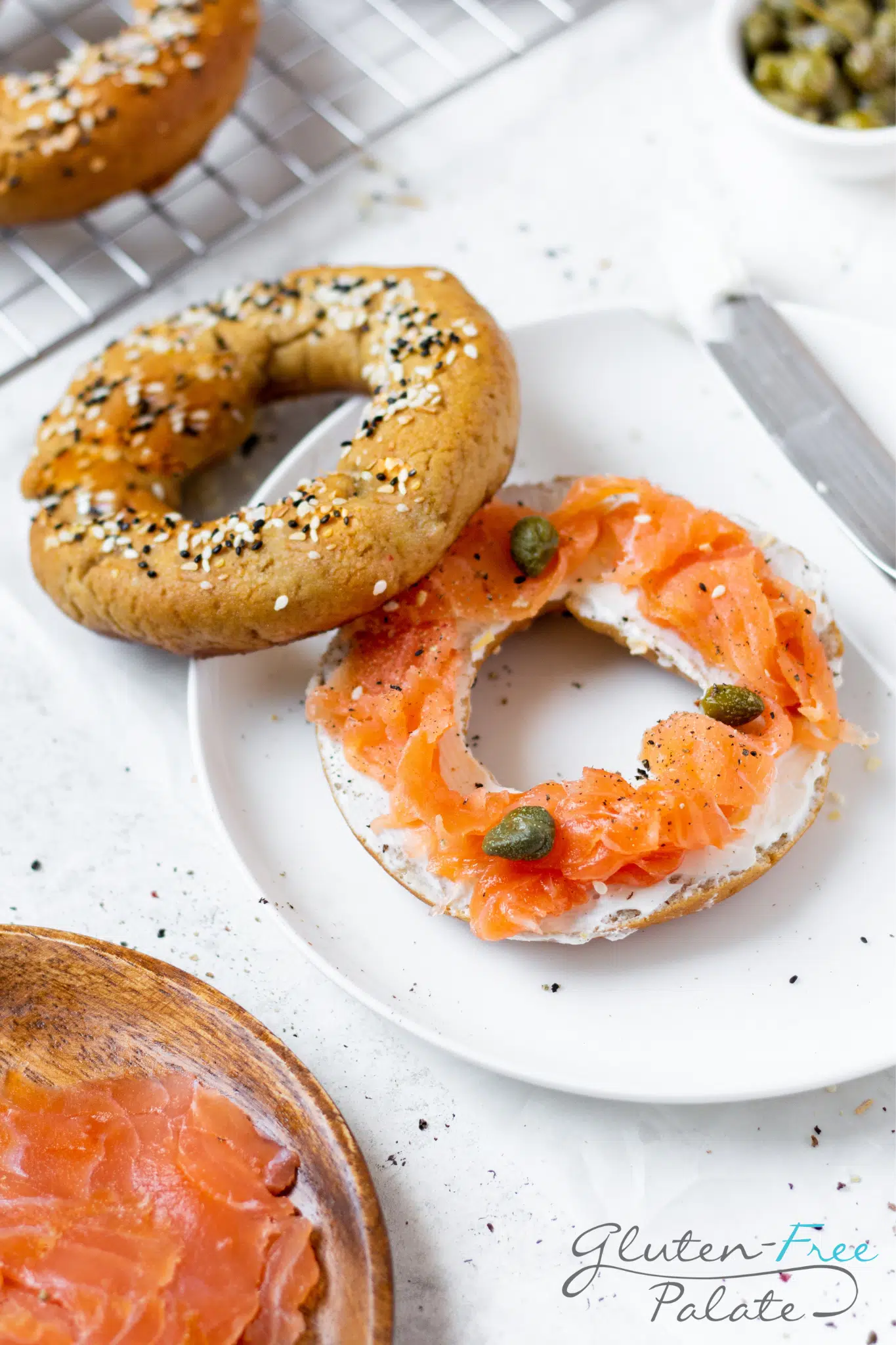 a sliced bagel on a plate topped with cream cheese, lox, and capers. 