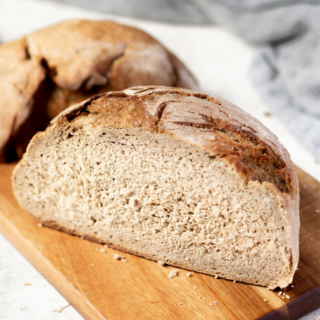 a round loaf of gluten-free sourdough bread cut in half to show the lovely crumb.