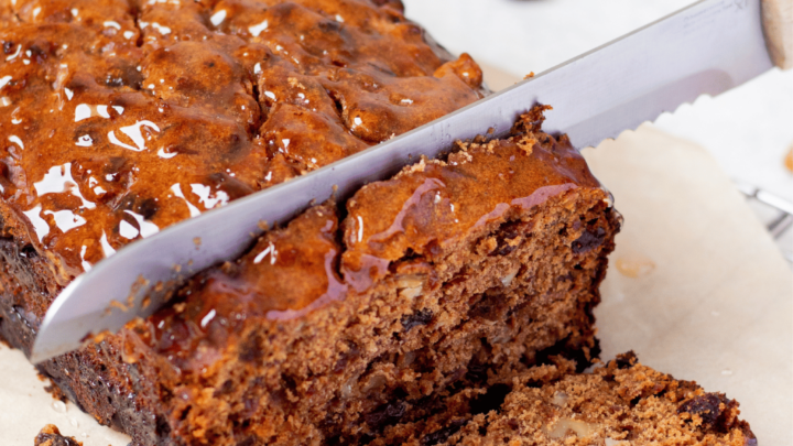 a loaf of gluten free fruit cake, sliced by a large knife.