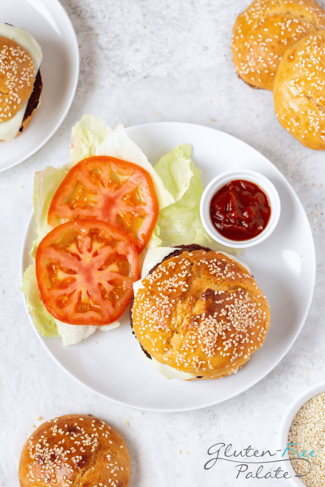 Gluten-Free Hamburger Bun with a patty on a white plate with garnishes.