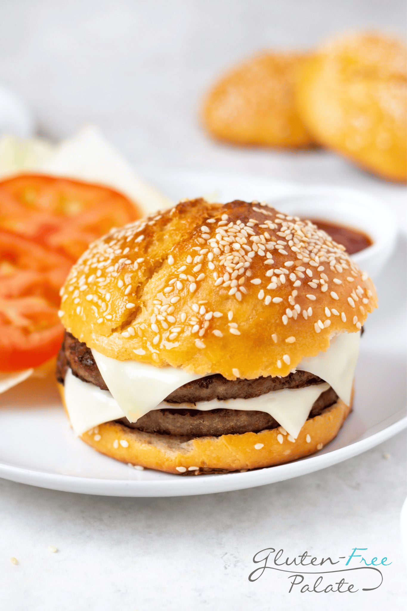 Gluten-Free Hamburger Bun with a patties on a white plate with garnishes.