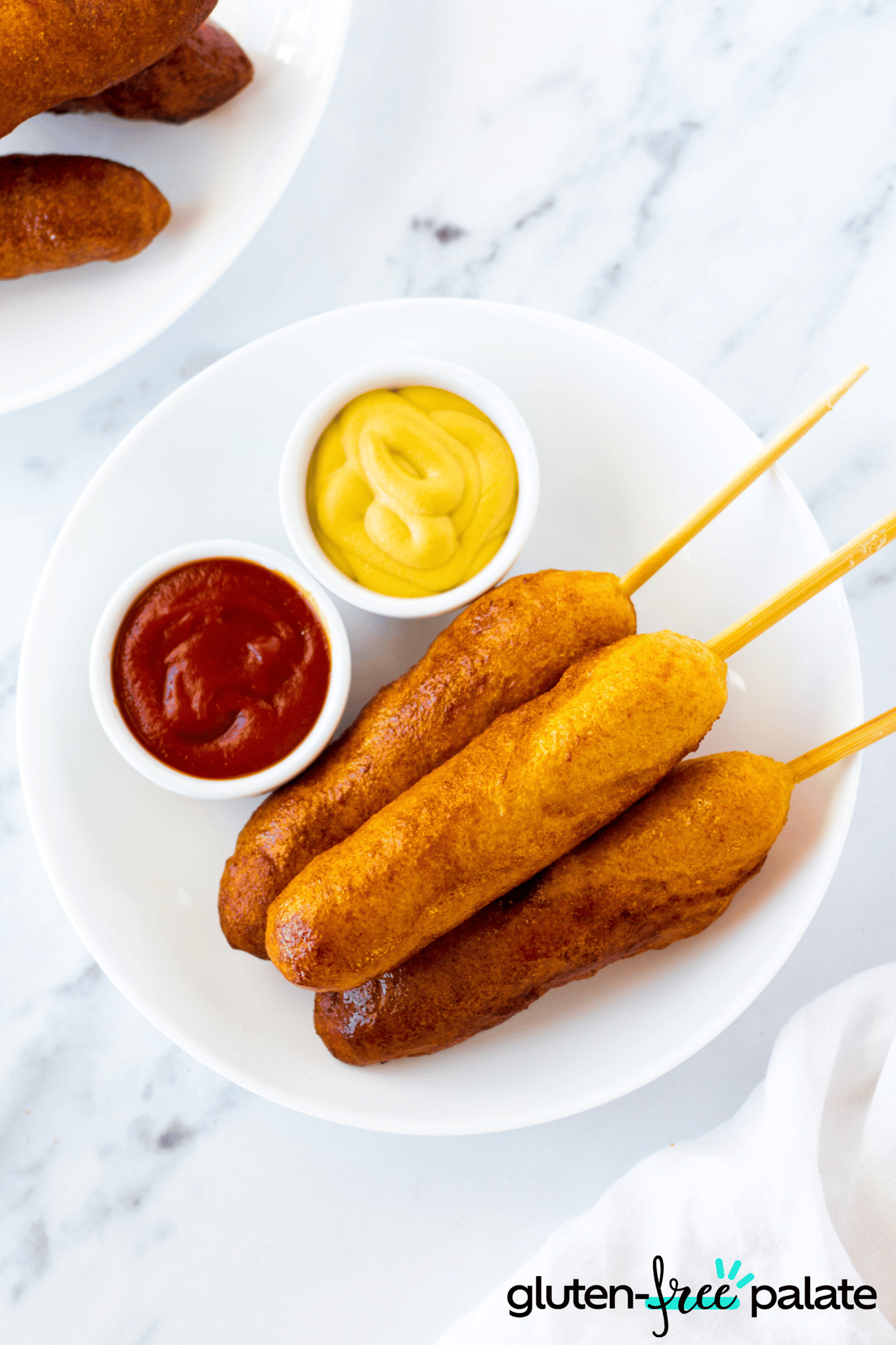 Gluten-Free Corn Dogs on a white plate with dipping sauce.