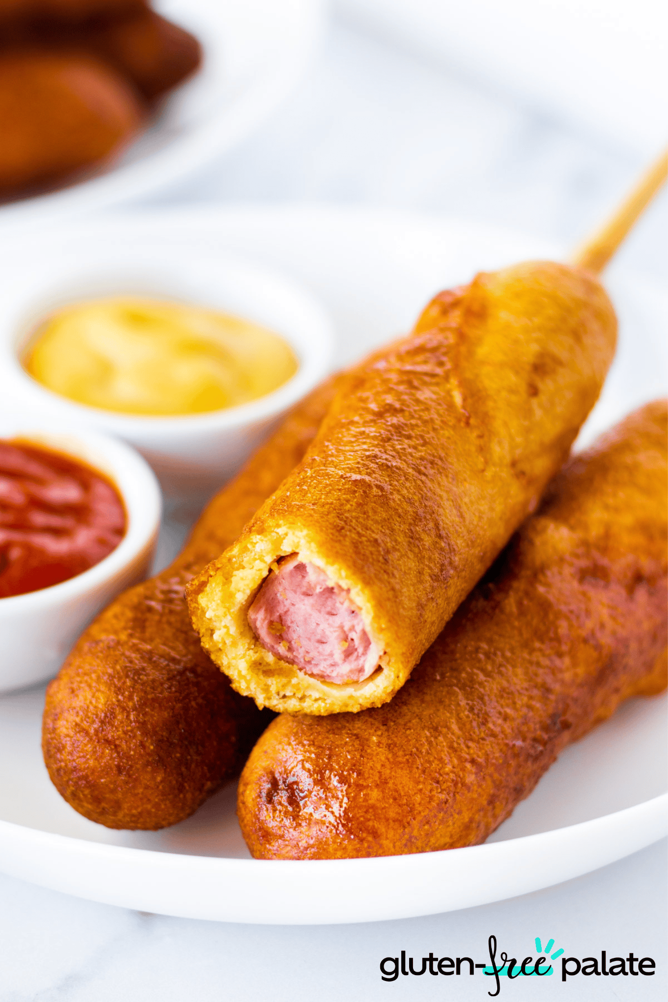 Gluten-Free Corn Dogs on a white plate with dipping sauce.
