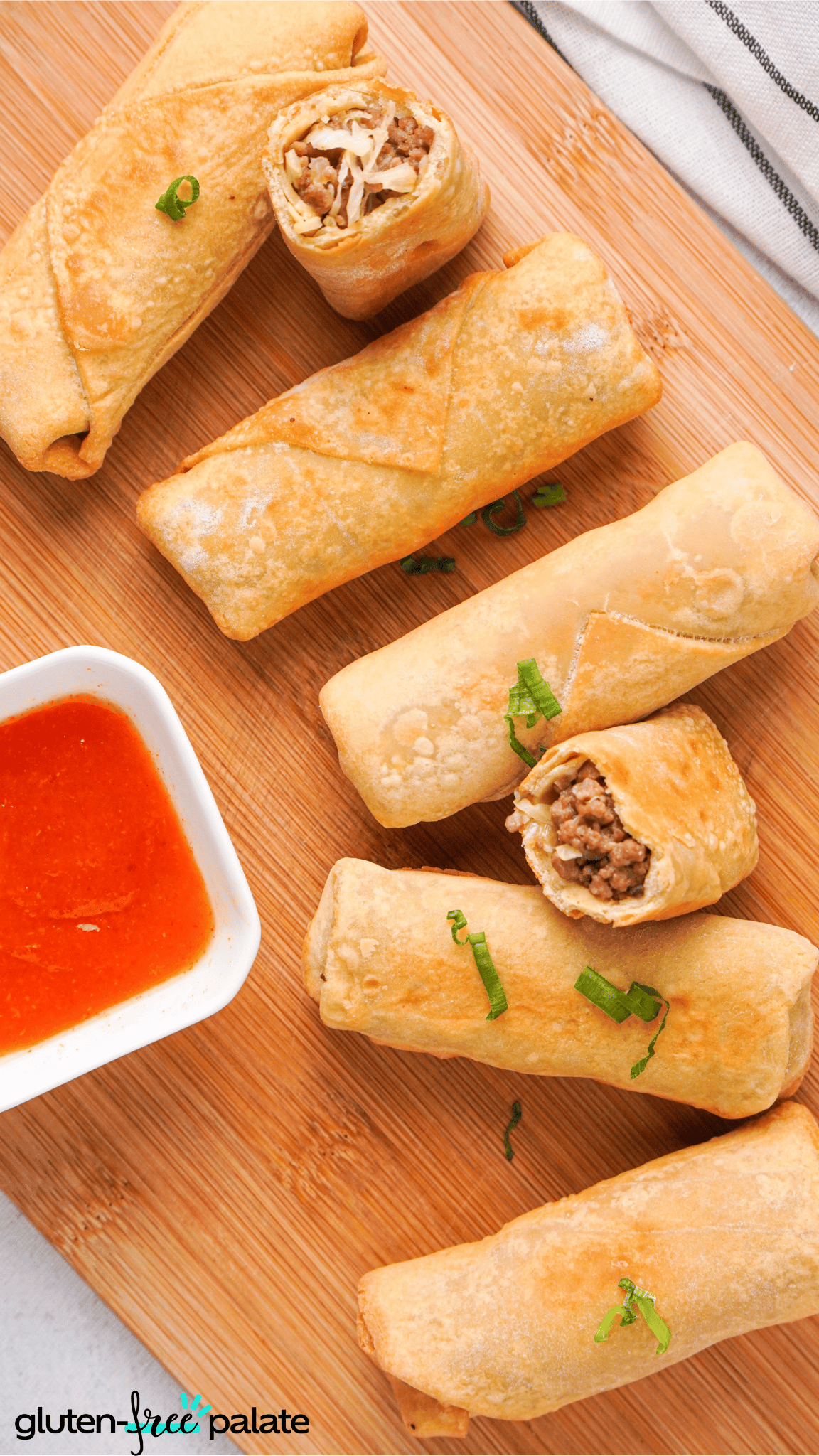 gluten-free egg rolls on a wooden board with dipping sauce.