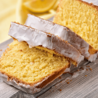 Gluten-free lemon drizzle cake sliced on a board.
