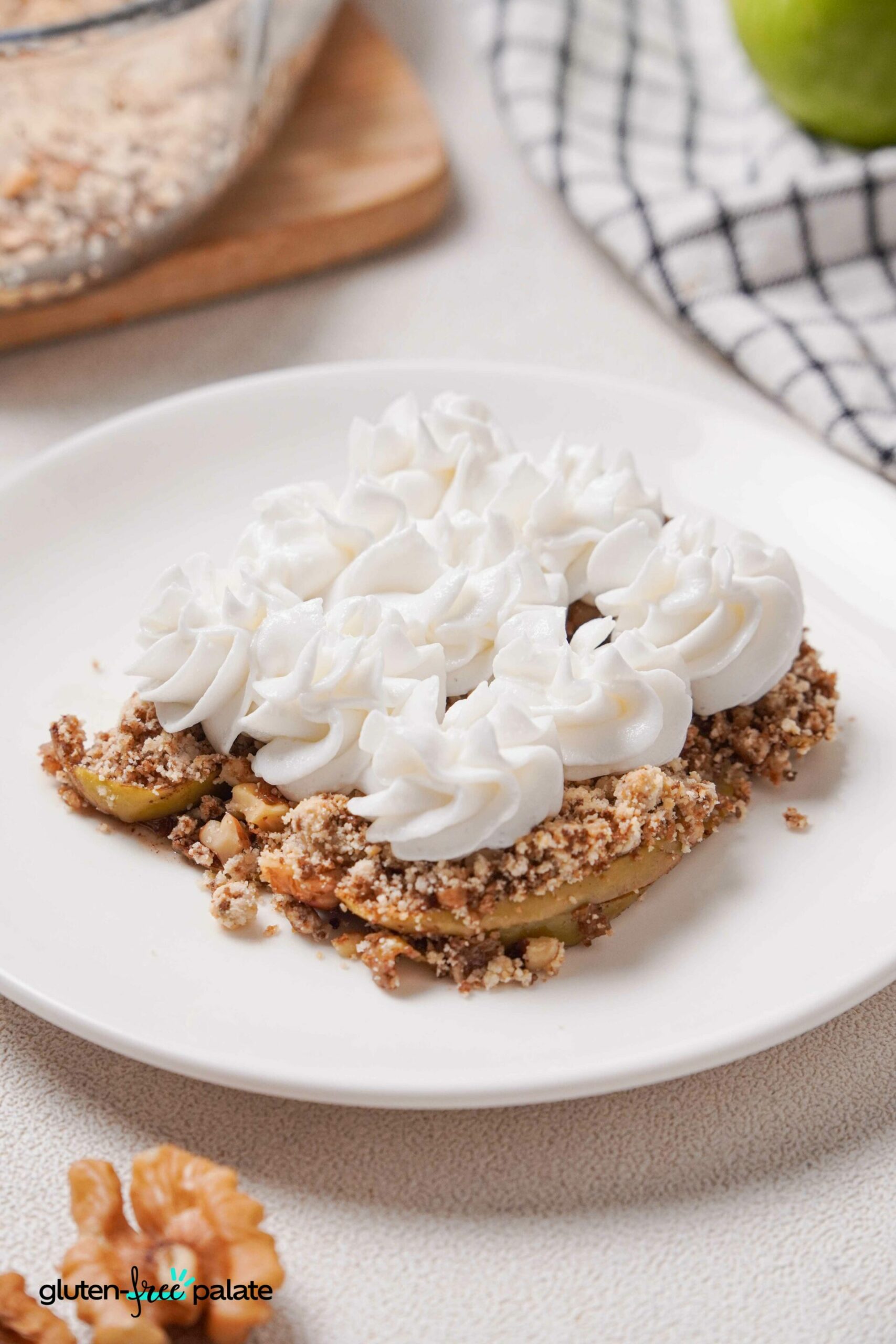 gluten-free apple crumble on a white plate with cream on top.