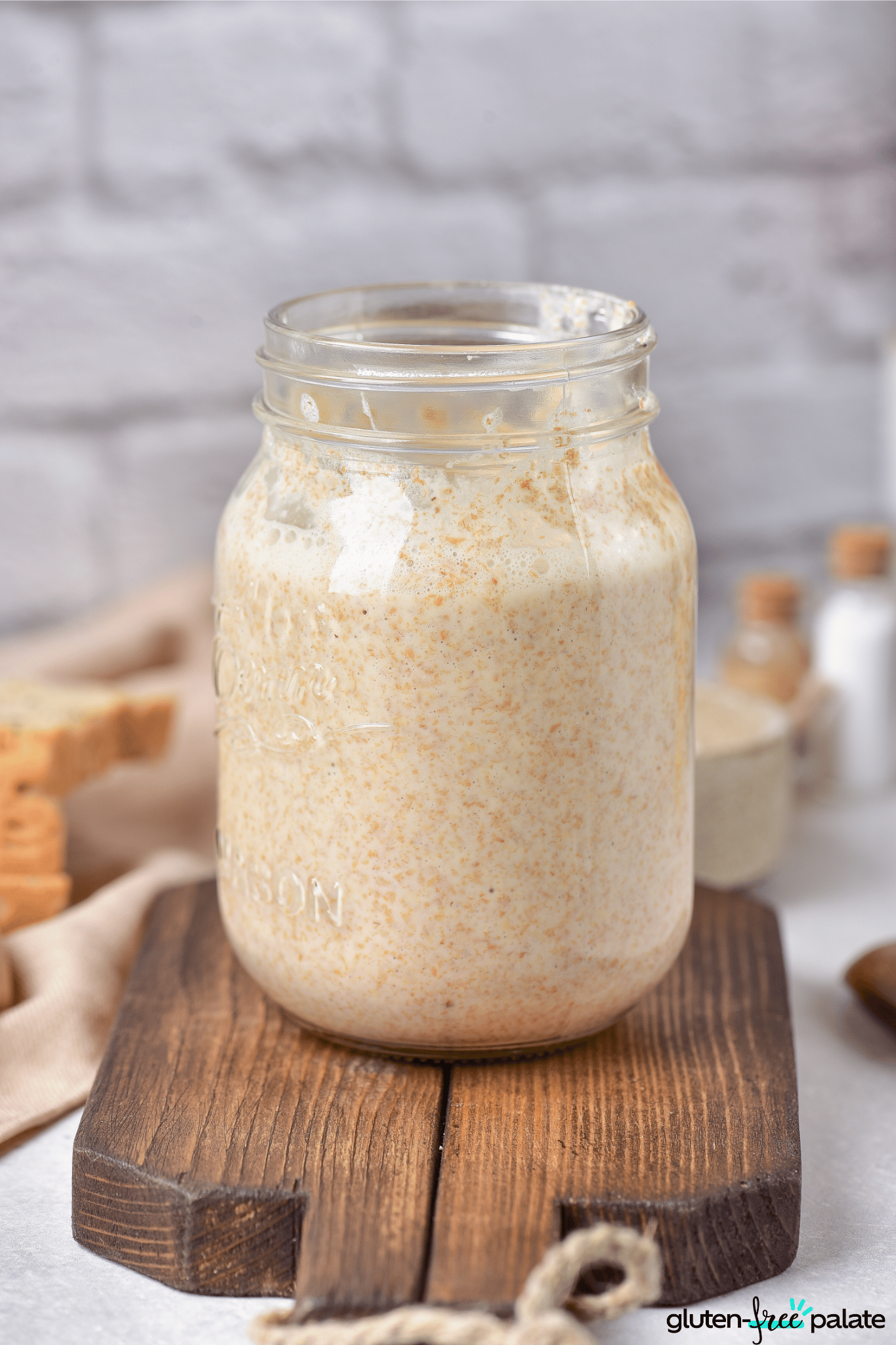 gluten-free sourdough starter in a glass jar on a board.