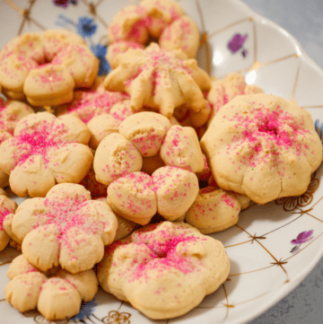 gluten-free spritz cookies with pink sugar on a white serving plate.