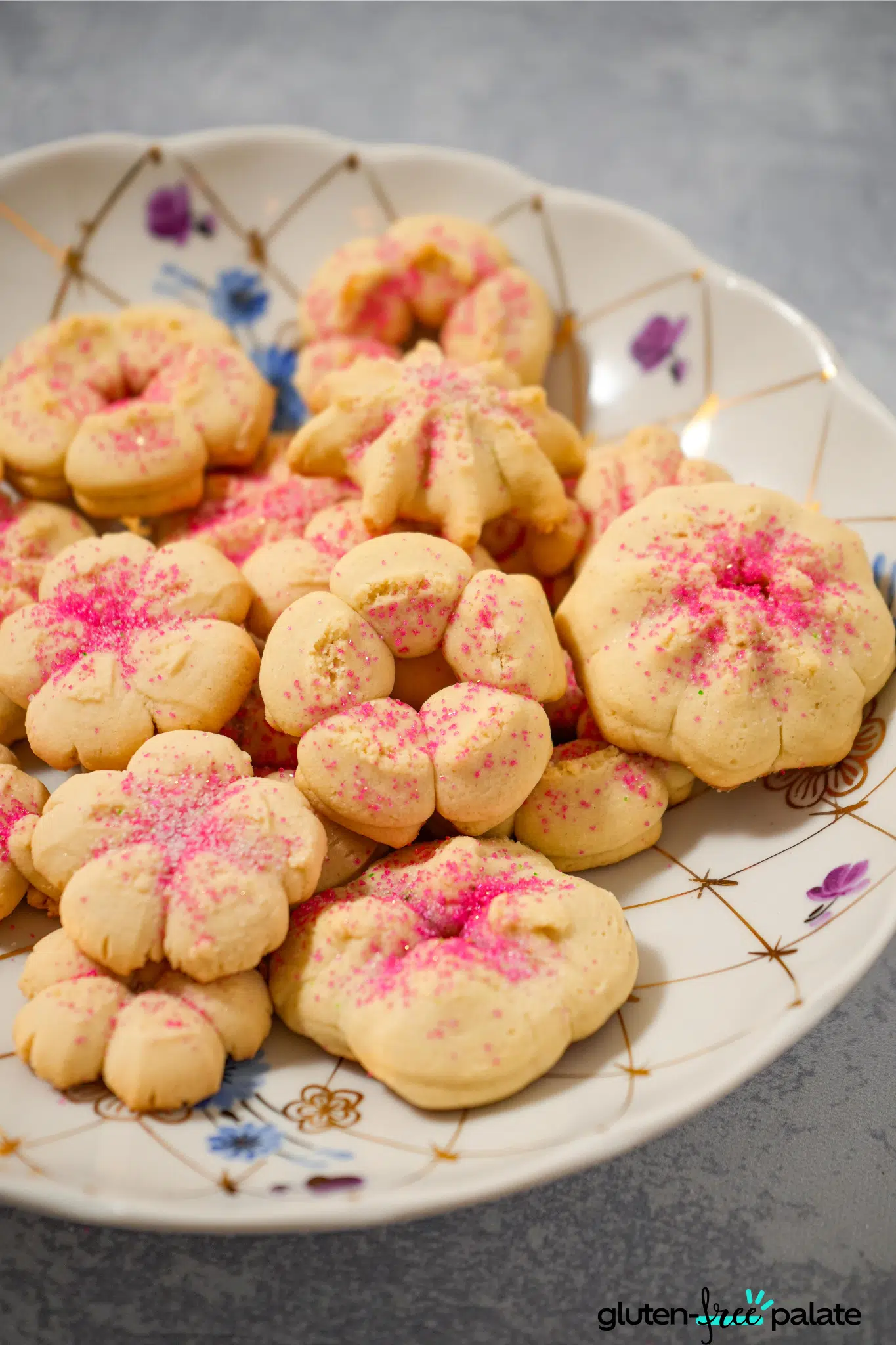 gluten-free spritz cookies with pink sugar on a white serving plate.