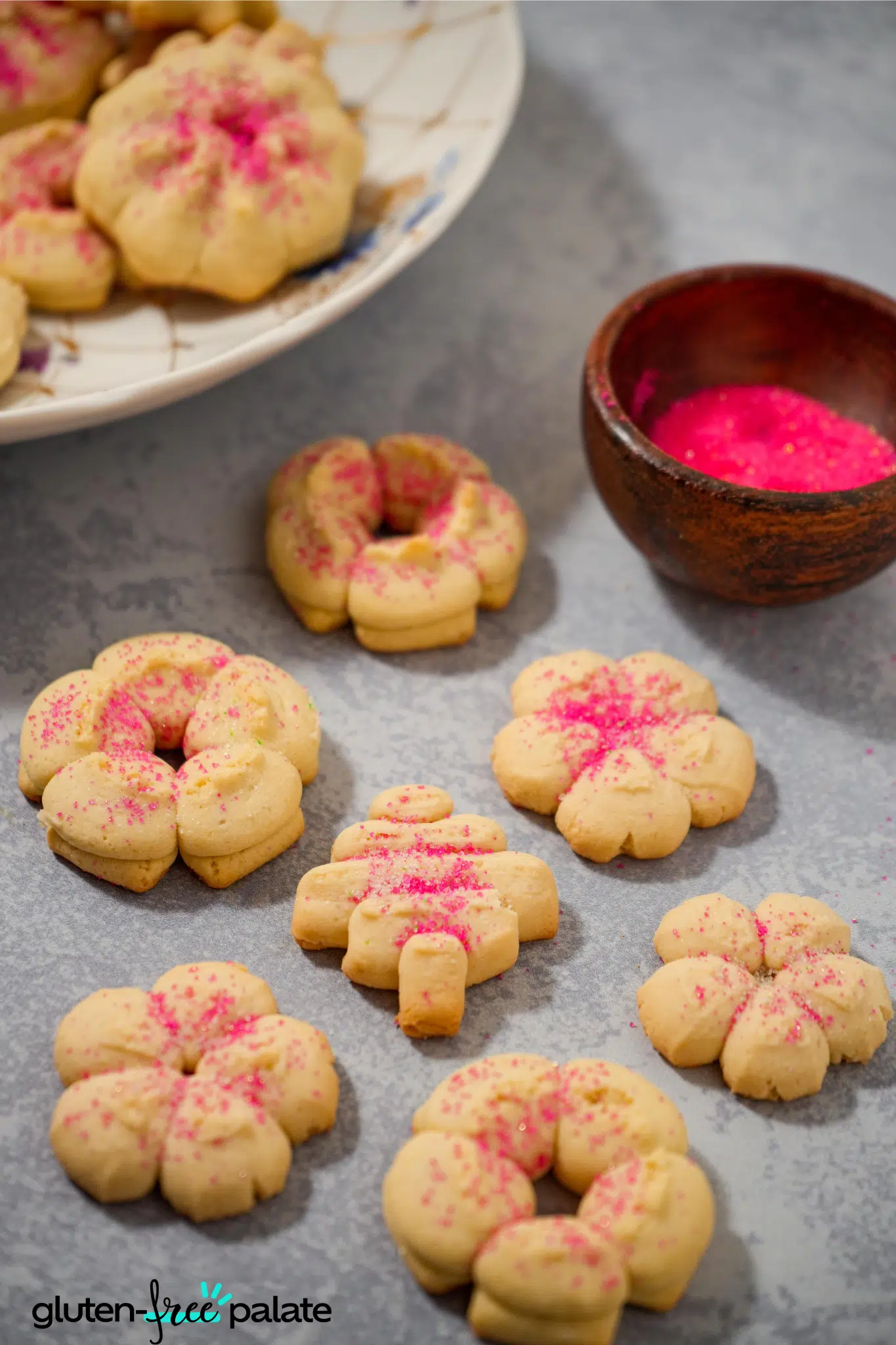 gluten-free spritz cookies being decorated with pink sugar.