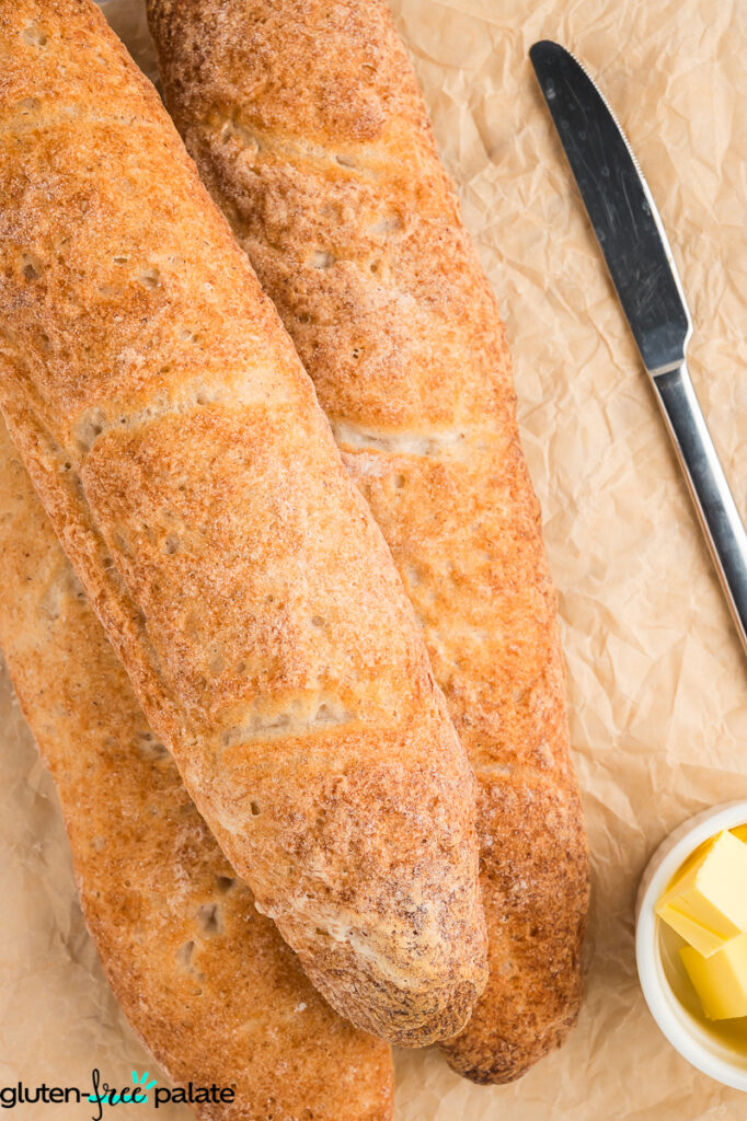 Loaves of baguette on a surface with butter and a buter knife.
