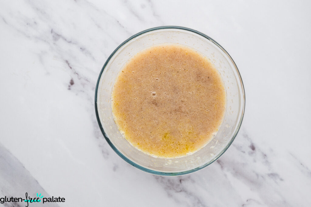 Psyllium gel, yeast mixture, olive oil, and vinegar combined in a bowl, slightly frothy.