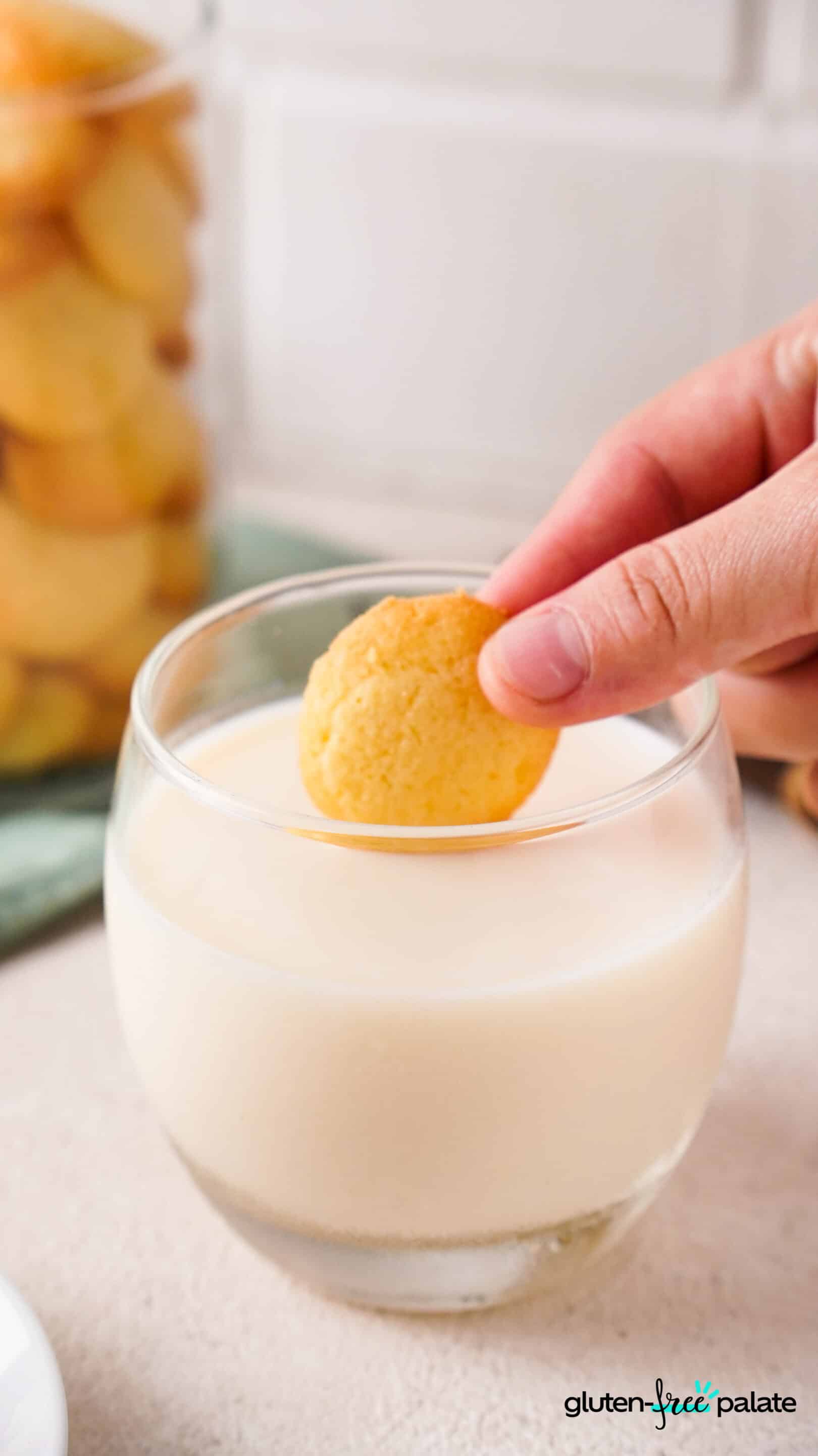 gluten-free vanilla wafer being dipped in milk.