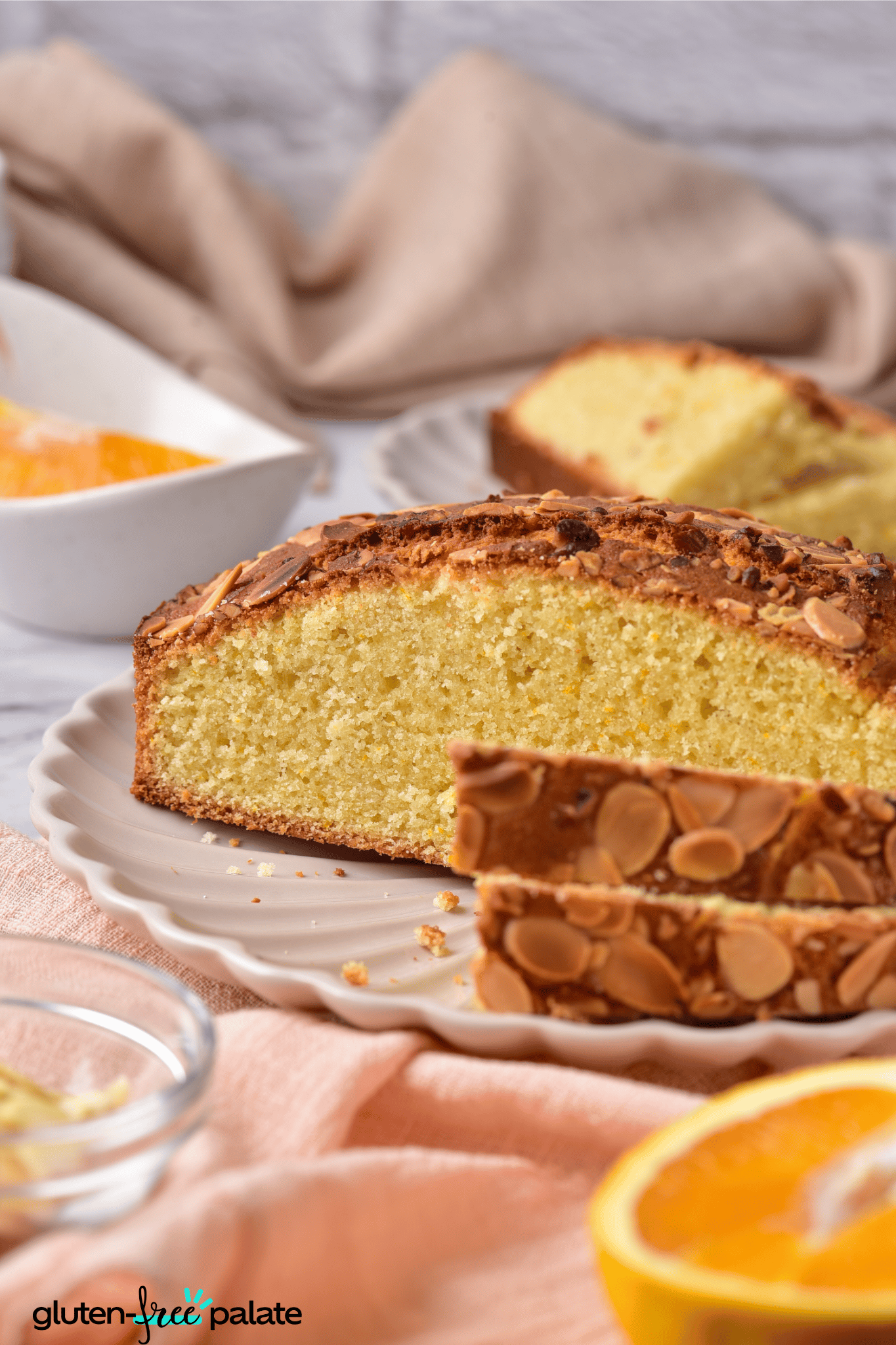 a sliced gluten-free almond cake on white cake plate.