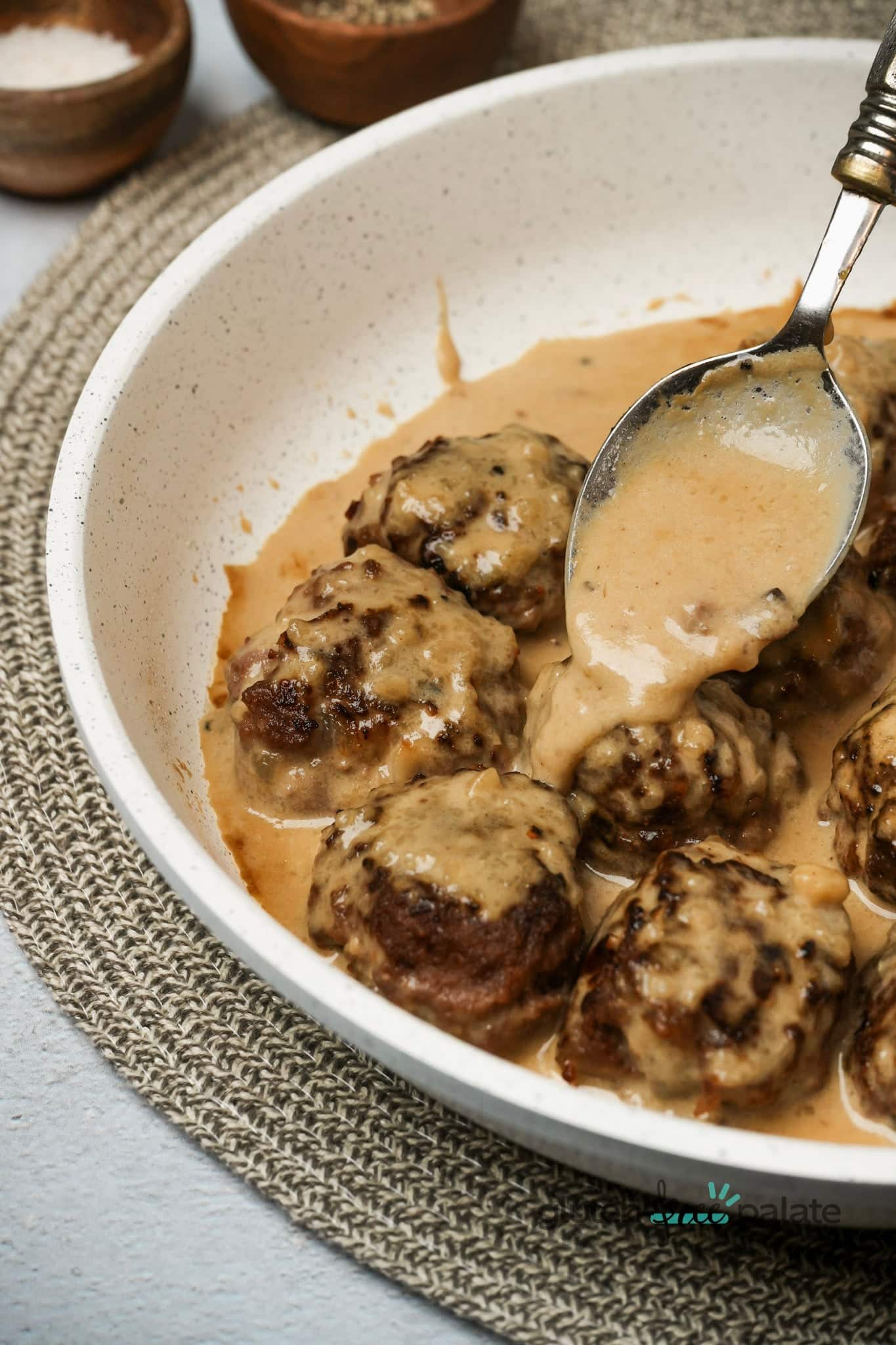 Gluten-Free Swedish meatballs with sauce being poured over them.