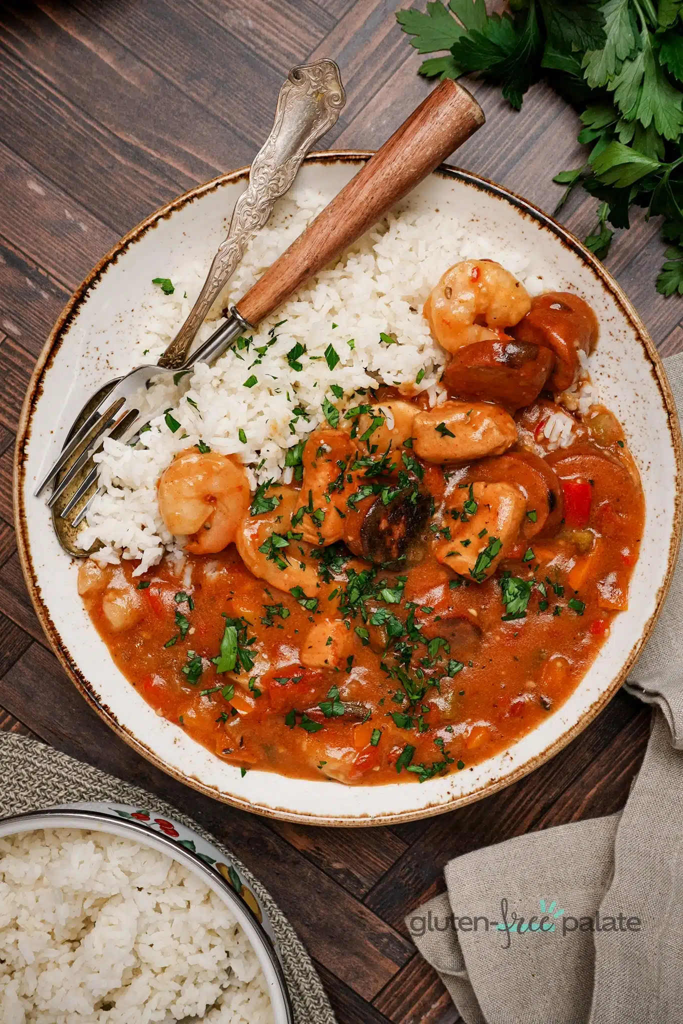 Gluten-free gumbo on a white plate with a fork and spoon.