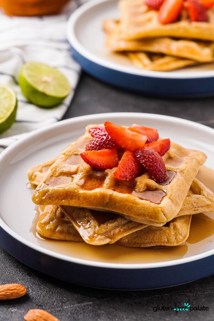 Paleo waffles on a white plate with strawberries on top.