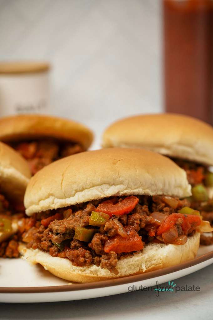 Close up view of a gluten-free sloppy joes on a white plate showing the filling in a gluten-free bun