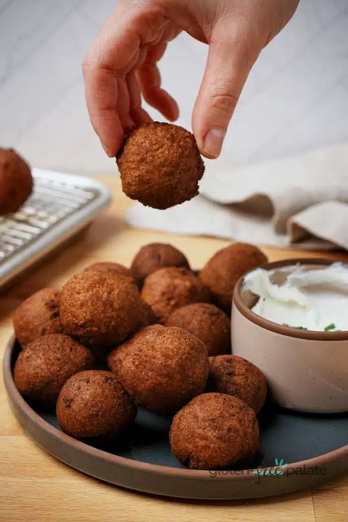 Gluten-free hush puppies with a hand holding one.