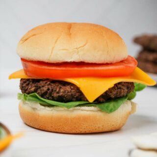 Gluten-free black bean burger patties in a hamburger bun with lettuce, cheese, and tomato.