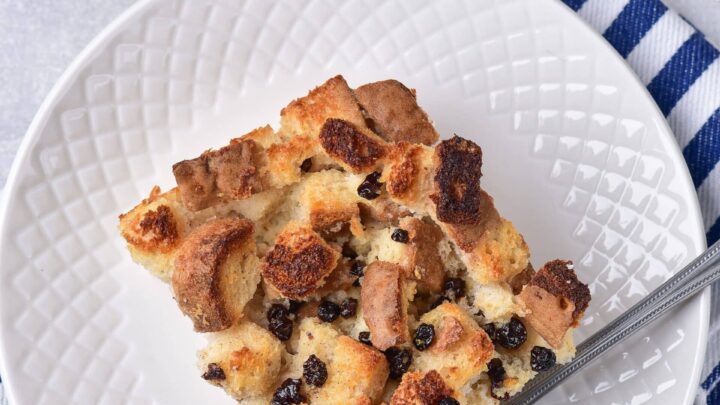 Overhead view of a slice of gluten-free bread pudding ion a white plate with a fork.