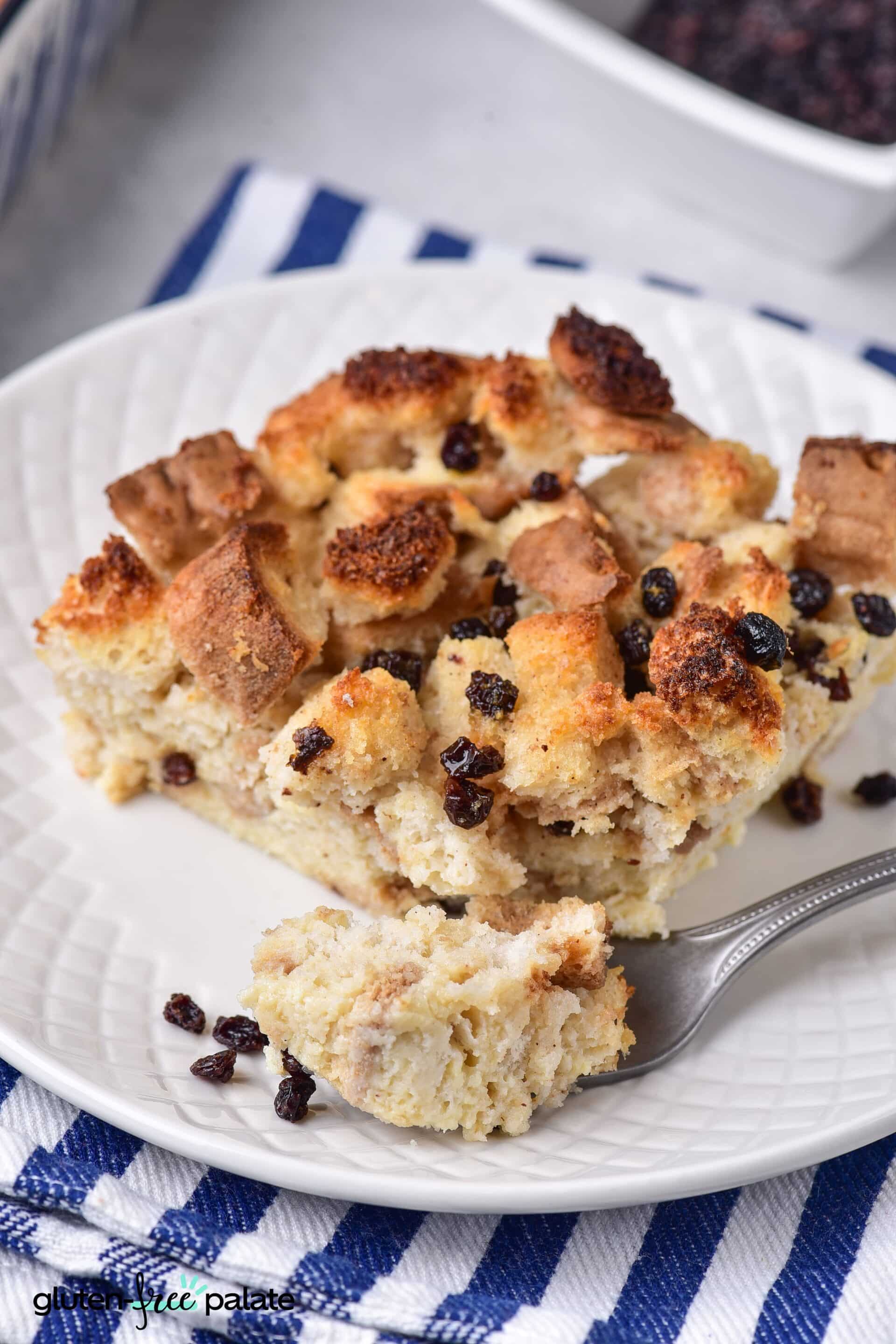 A slice of gluten-free bread pudding ion a white plate with a fork.