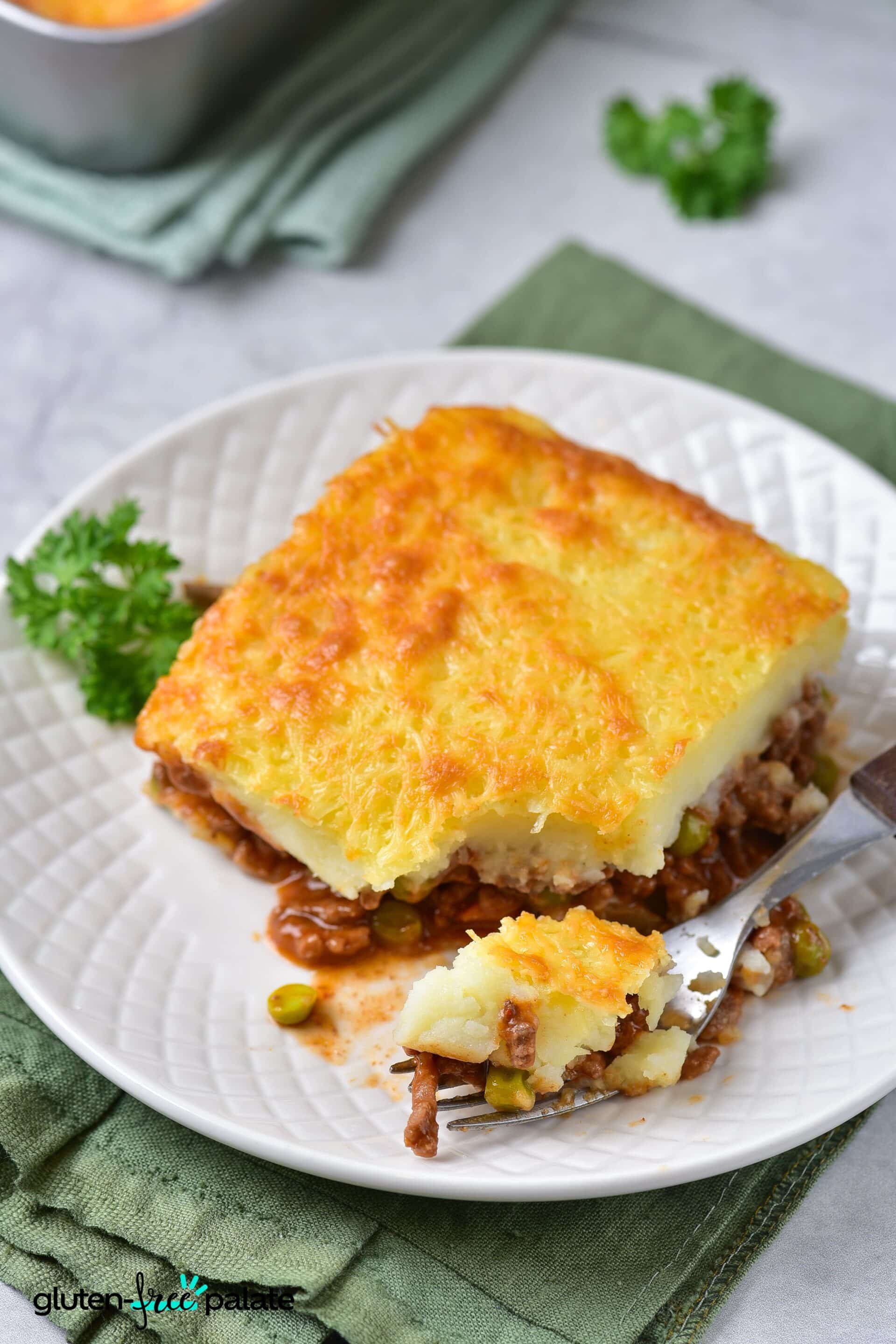 A slice of gluten-free shepherds pie on a white plate with a fork