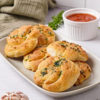 Gluten-free garlic knots on a white plate with toppings.