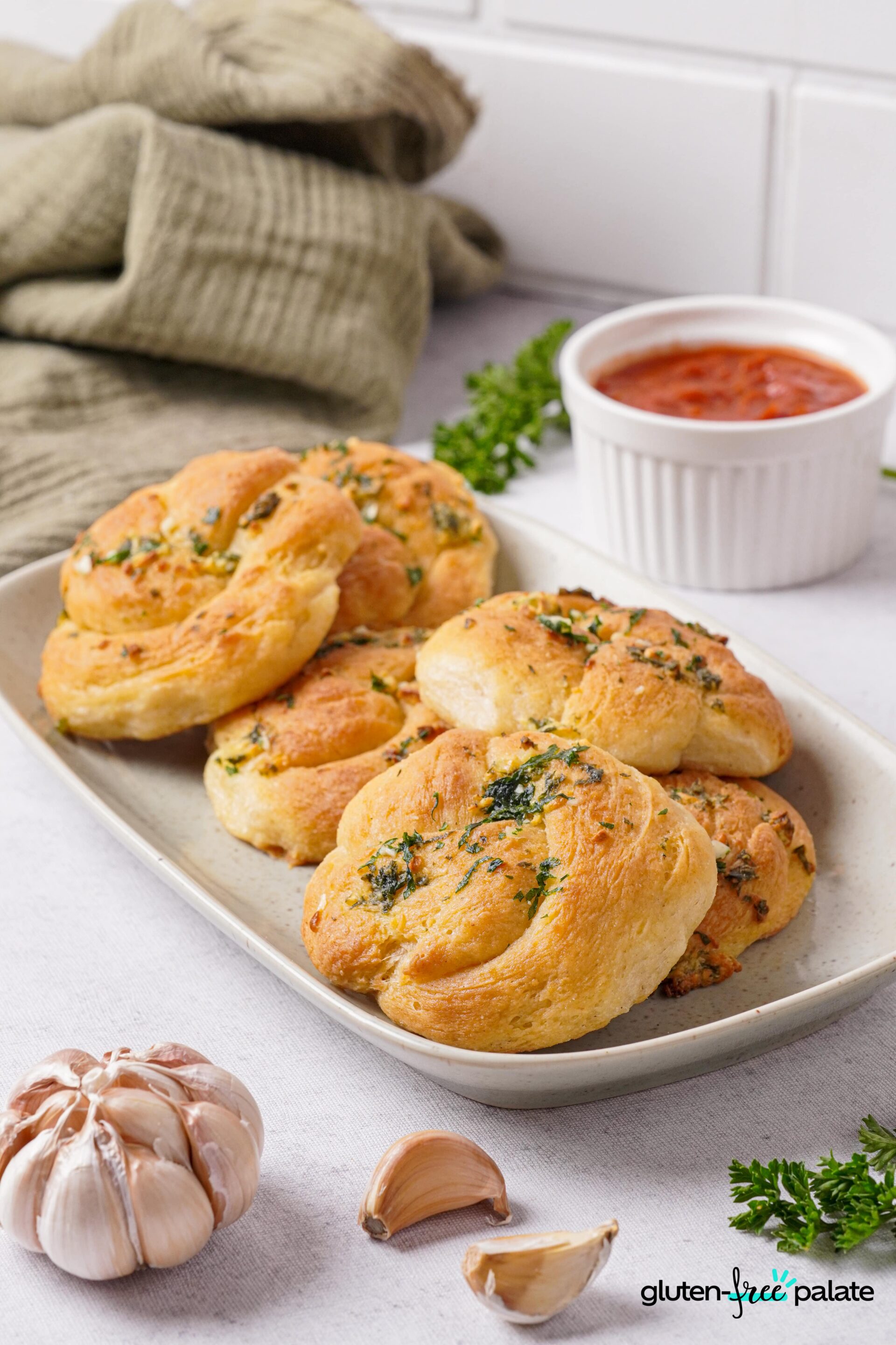 Gluten-free garlic knots on a white plate with toppings.