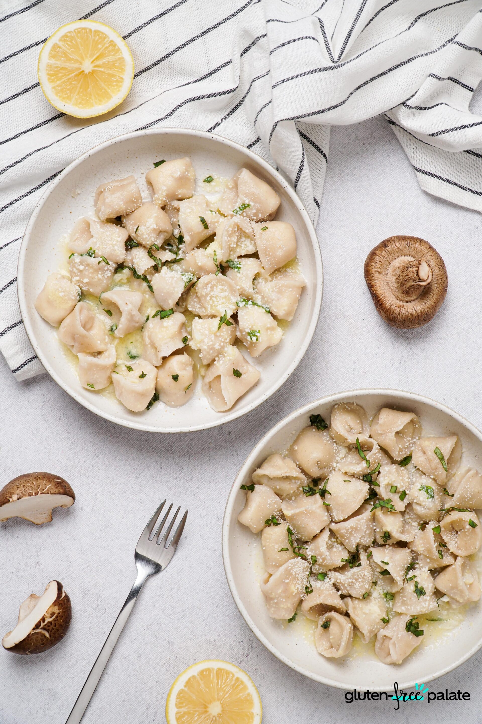 Gluten-Free Tortellini on a white plates with parmesan and basil sprinkled on top with a silver fork holding the tortellini up.