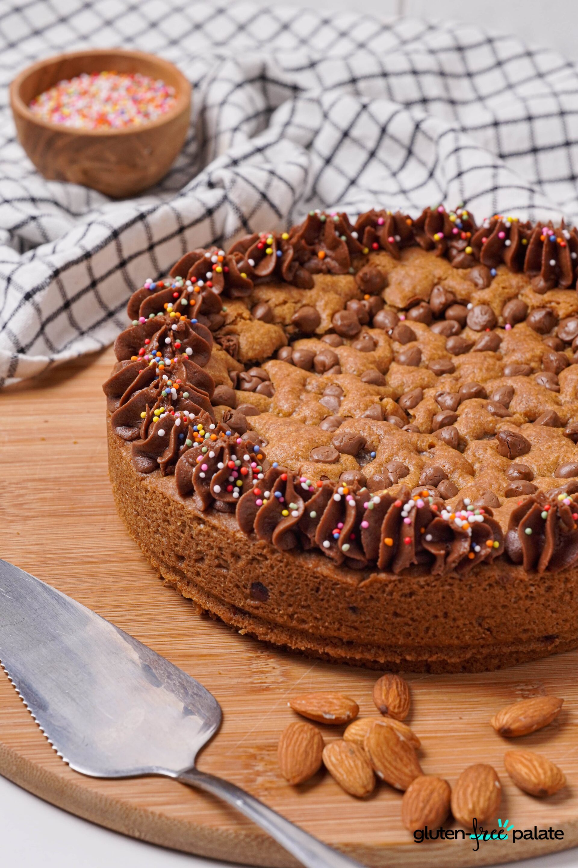Gluten-free cookie cake on a brown board with a cake lifter.