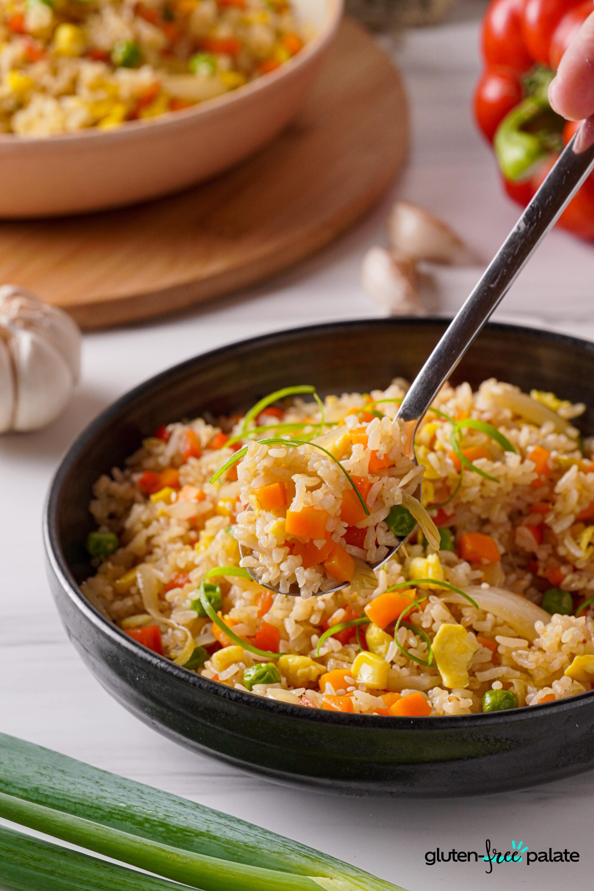 Gluten-free fried rice in a black bowl with a spoon in it.