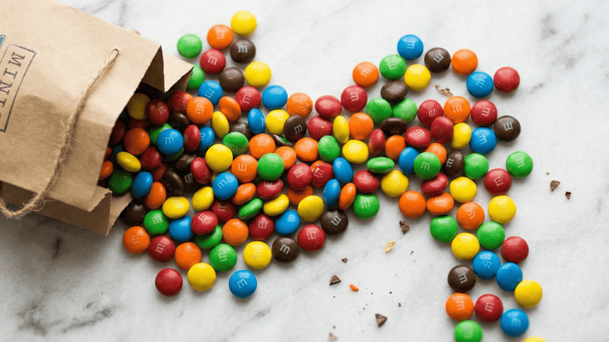 A bag spilled showing mms on a marble tabletop.