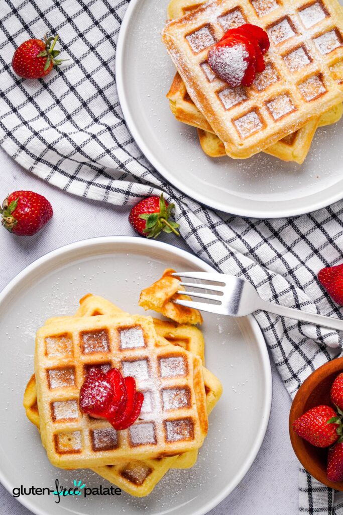 Gluten-free Belgian waffles on a plate topped with strawberries.