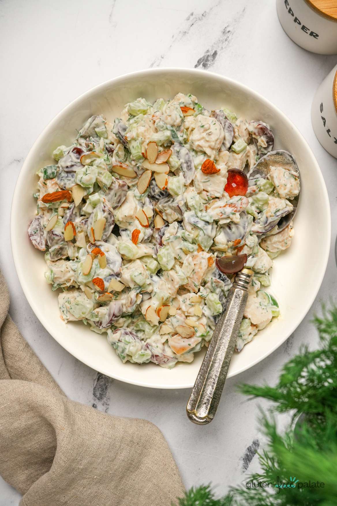 Gluten-free chicken salad in a white bowl with a serving spoon.