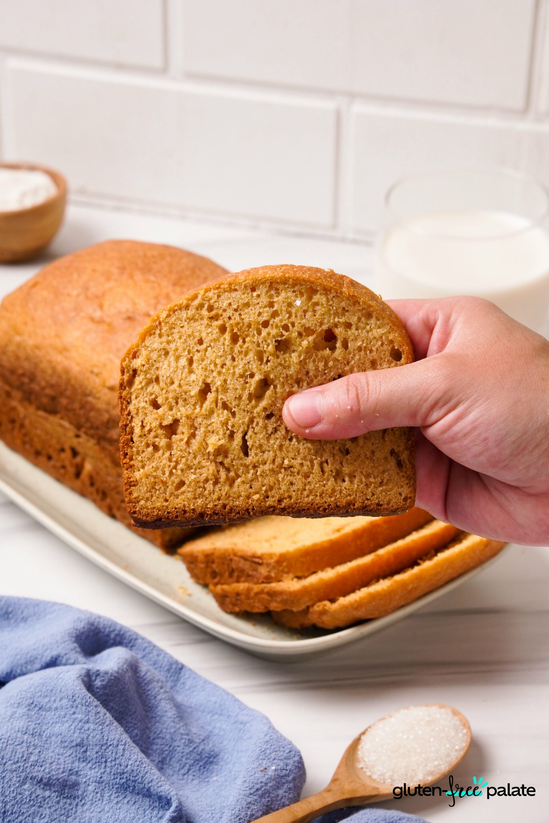 Gluten-Free Yeast-Free Bread sliced and once slice being picked up by a hand.