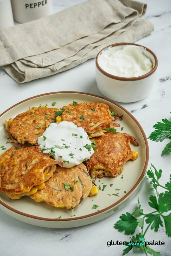 Gluten-free corn fritters on a plate with dipping sauce.