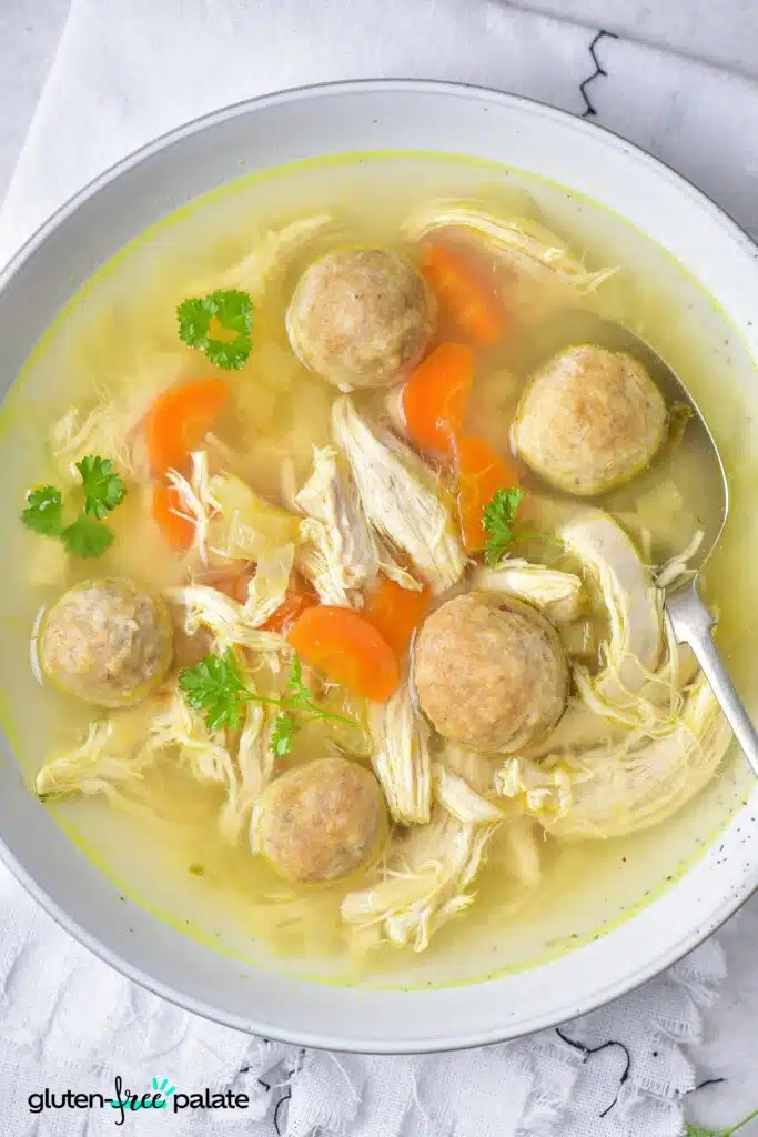 gluten-free matzo ball soup in a white plate with a spoon.
