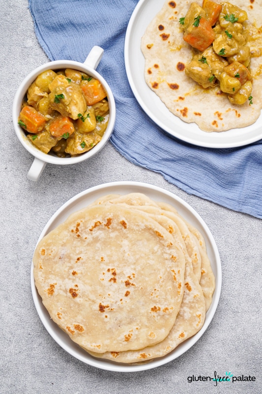 Gluten-free flatbread in a blue and white plate with curry in a white pot.