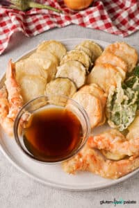 Gluten-free tempura on a white serving plate with a dipping sauce.