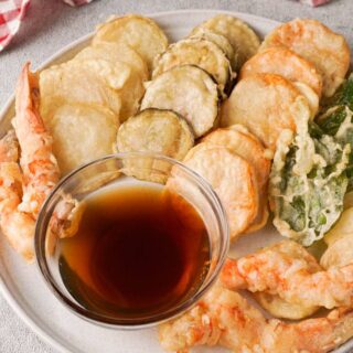 Gluten-free tempura on a white serving plate with a dipping sauce.