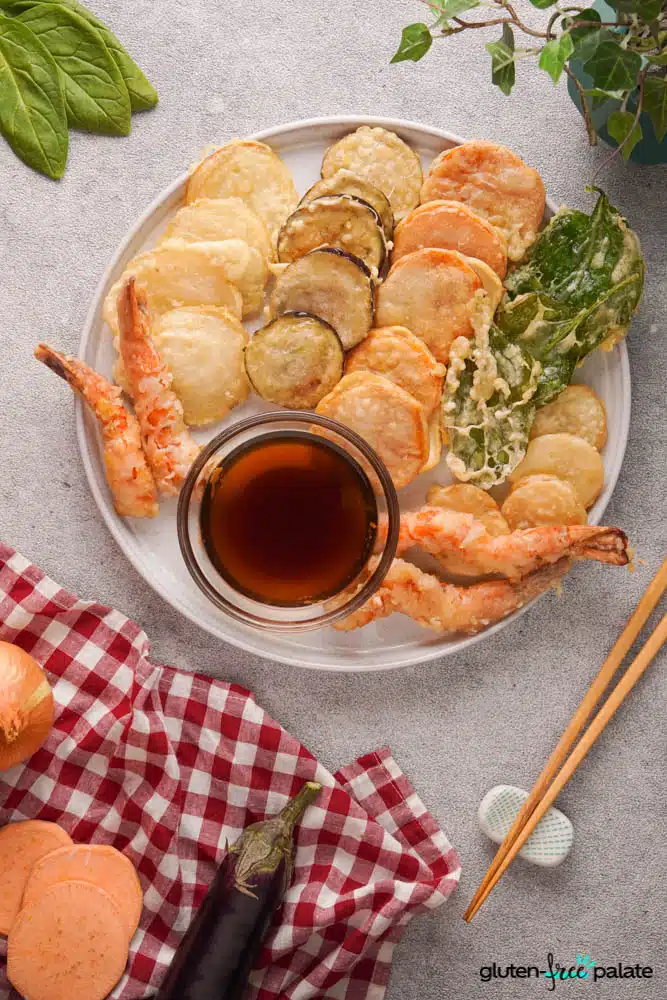Gluten-free tempura platter on a white serving plate with a dipping sauce.