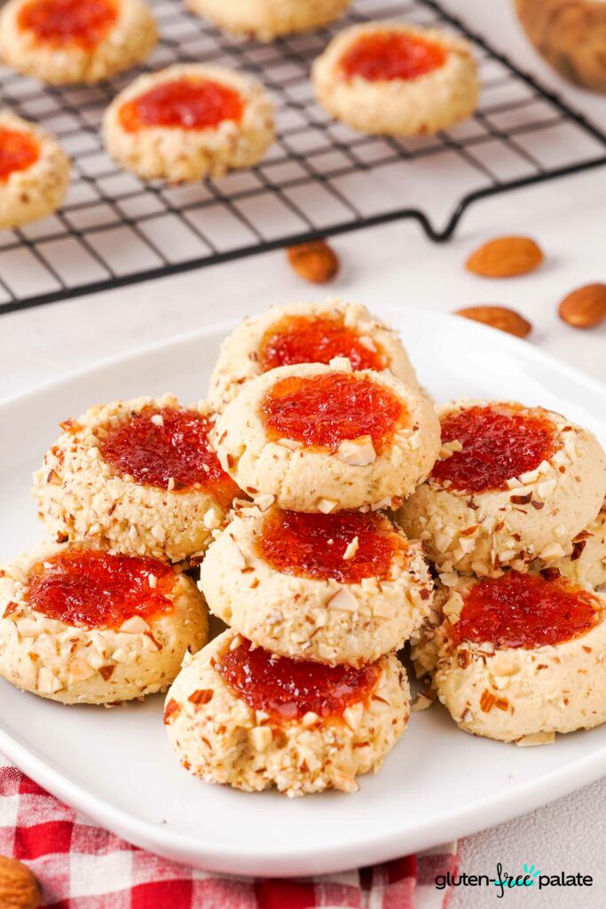 Gluten-free thumbprint cookies stacked on a white plate.